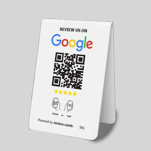 A Google Tap or Scan Table Tents card with a QR code and instructions to review on Google. It displays five stars, icons for scanning or tapping the QR code, and is supported by review.cards. The centered QR code has text above and below it. The background is gray. Perfect Google Tap or Scan Table Tents solution.