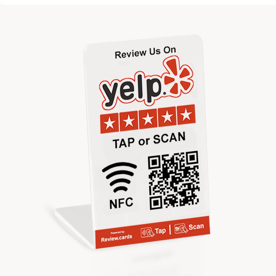 A small plastic stand displays a sign urging customers to review on Yelp. Featuring the Yelp logo, five red stars, and instructions to "TAP or SCAN," it includes a Wi-Fi symbol for NFC and a QR code. The base showcases icons for tap and scan with the Yelp Tap or Scan Smart Review Cards - Free Delivery.