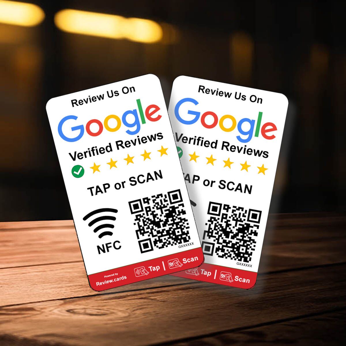 Two Hospitality Bundle 1 table tents with "Review Us On Google Verified Reviews" are displayed on a wooden surface. Both tents feature a five-star rating, a QR code, and icons for NFC, tapping, and scanning. The background is dark and blurred, perfectly highlighting the table tents.