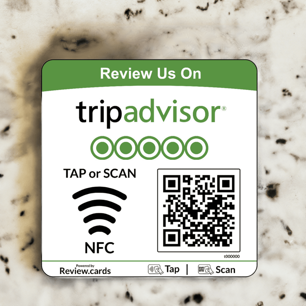 A TripAdvisor NFC Review Plate placed on a marble surface invites users to review the establishment on TripAdvisor by using NFC. It features a QR code, an NFC tap icon, and prompts to "Tap or Scan." The TripAdvisor logo and five green stars are prominently displayed at the top.